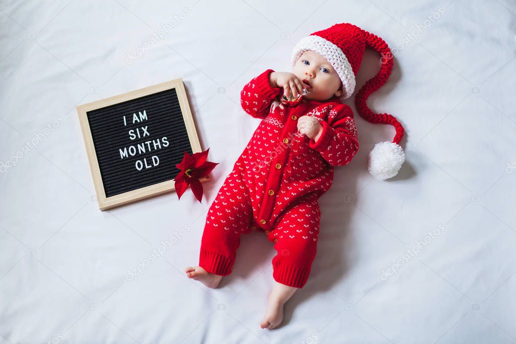 6 Six months old baby laying down on white background wearing Santa Claus costume. Flat lay composition.