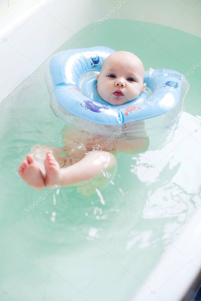 Newborn baby bathing with neck swimming ring.