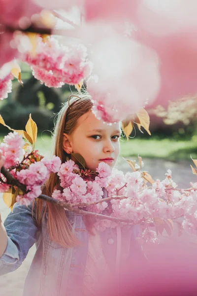 Retrato autêntico de menina bonita escola posando entre florescendo árvores sakura japonesas . — Fotografia de Stock