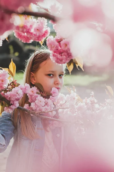 満開の桜の中にポーズをとる可愛い女の子の本物の肖像画. ストック画像
