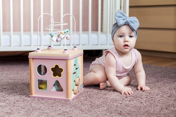 Schattig baby meisje spelen met houten activiteit speelgoed. — Stockfoto