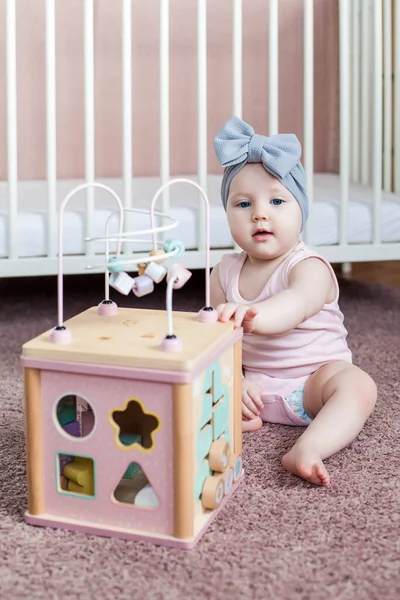Nettes Baby-Mädchen spielt mit Holzspielzeug. — Stockfoto