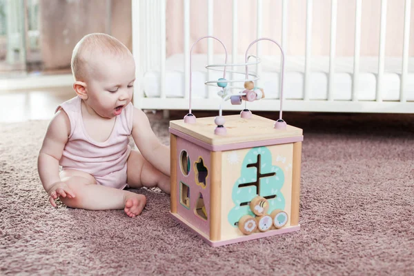 Nettes Baby-Mädchen spielt mit Holzspielzeug. — Stockfoto