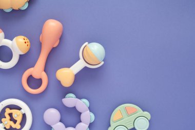 Bebek çıngıraklı bebeklerin renkleri ve açık mor arkaplandaki metin için alanı olan düz bir kompozisyon..