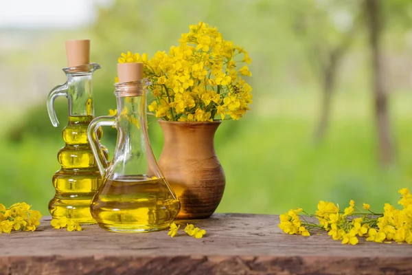 rapeseed oil (canola) and rape flowers on wooden table