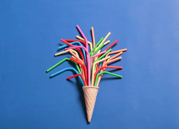 Cono de helado con pajitas coloridas para beber en la espalda azul brillante —  Fotos de Stock