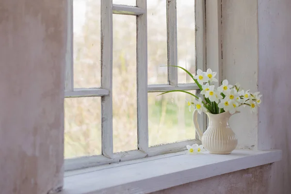 Narcisos en jarra sobre alféizar de ventana — Foto de Stock