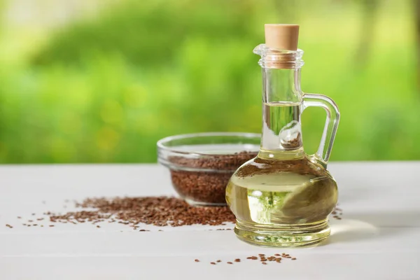 Semillas de lino y aceite de linaza en una jarra de vidrio sobre una mesa de madera — Foto de Stock