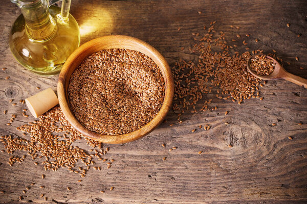 flax seeds and linseed oil in a glass jug on a wooden table