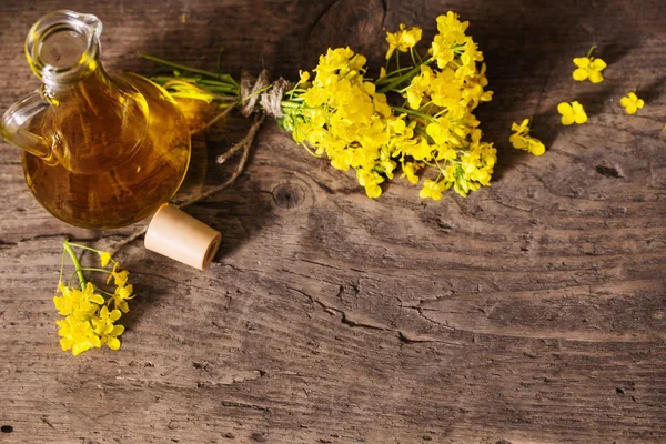 Řepkový olej (kanola) a řepkové květiny na dřevěném stole — Stock fotografie