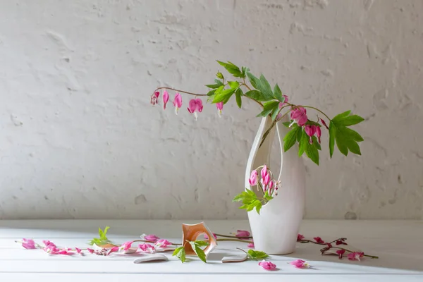 Flores cor-de-rosa em vaso quebrado no fundo branco velho — Fotografia de Stock