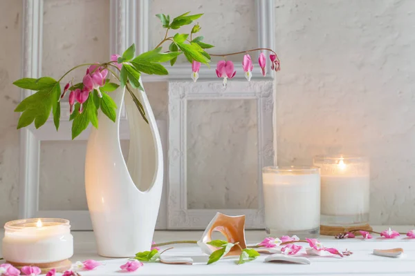 Fiori in vaso con candele su sfondo parete bianca — Foto Stock