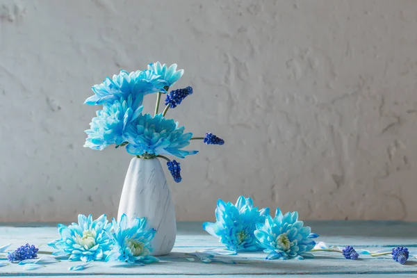 blue flowers in vase on white grunge background