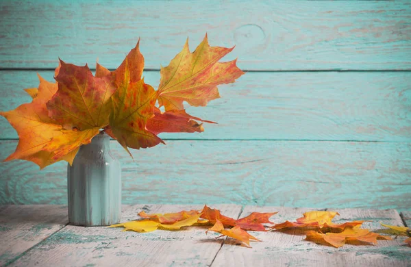 Maples in vase on wooden background — Stock Photo, Image