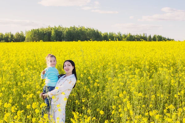 Flicka med mor i rapsfält — Stockfoto