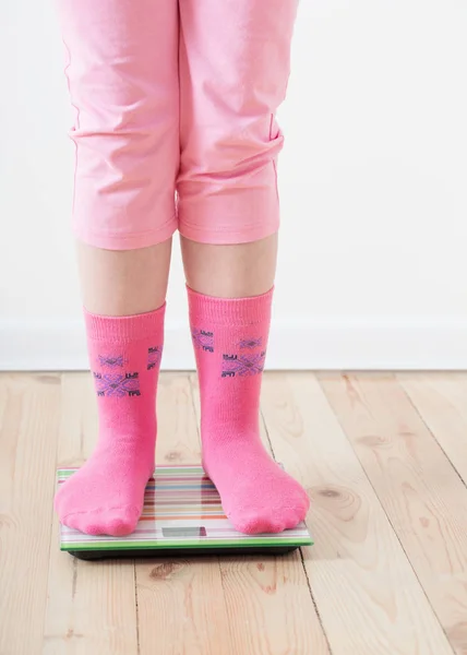 Feet on scales on wooden floor — Stock Photo, Image