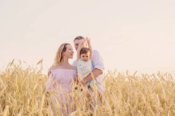 Famille heureuse dans le champ de céréales au coucher du soleil — Photo