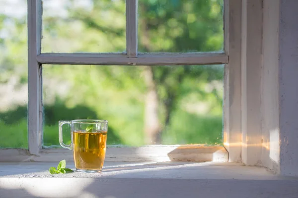 Té en taza de vidrio en el viejo alféizar de la ventana —  Fotos de Stock