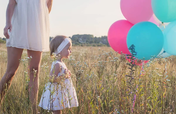 Gelukkig moeder en dochter met ballonnen buiten — Stockfoto