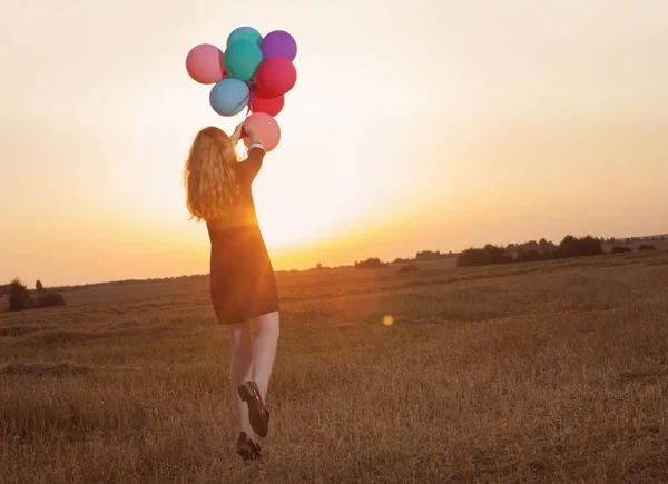 Tiener meisje met ballonnen bij zonsondergang — Stockfoto