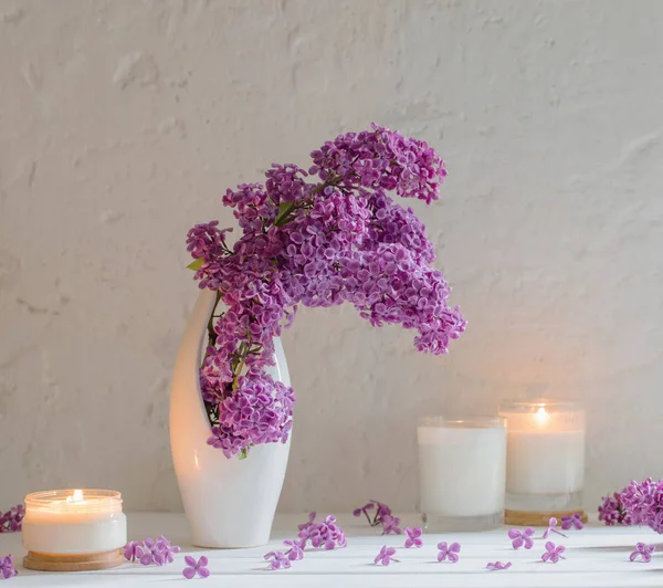 Цветы в вазе со свечами на фоне белой стены — стоковое фото