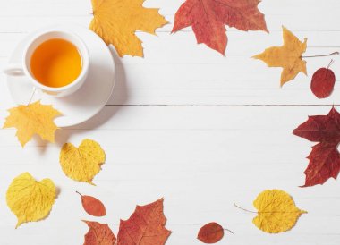 Ahşap arka planda sonbahar yapraklı bir fincan çay.