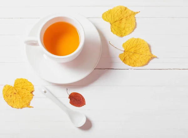 Xícara de chá com folhas de outono no fundo de madeira — Fotografia de Stock
