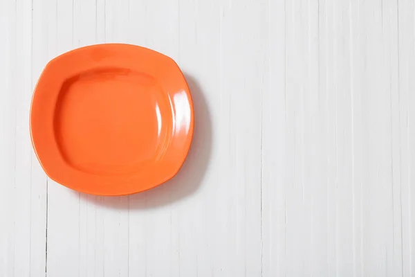 Оранжевая тарелка на белом фоне — стоковое фото