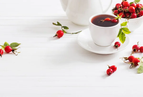 Tee mit Beeren einer Heckenrose auf einem hölzernen Hintergrund — Stockfoto