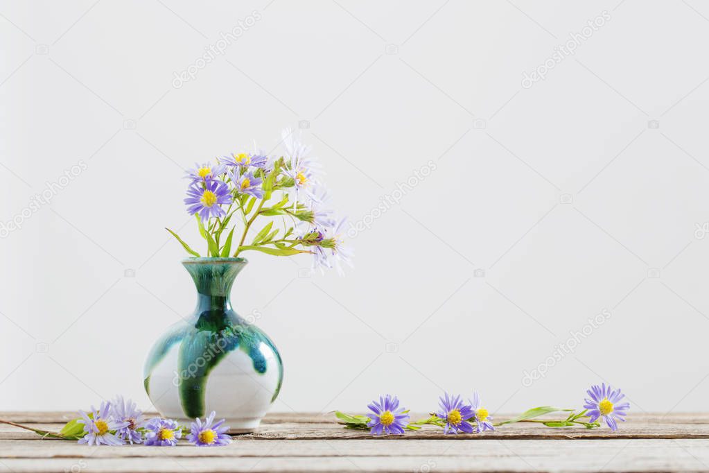 violet flowers in vase on wooden table
