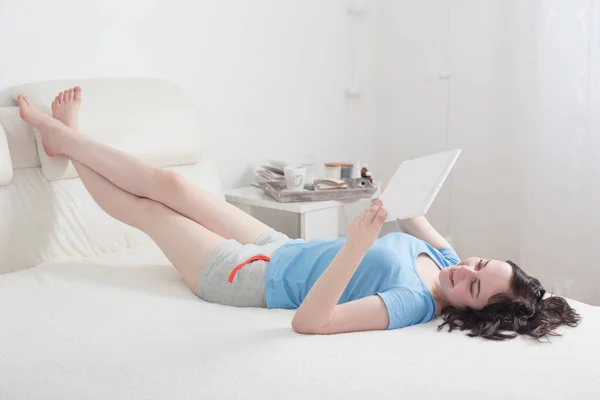 Chica joven en el dormitorio con la tableta — Foto de Stock