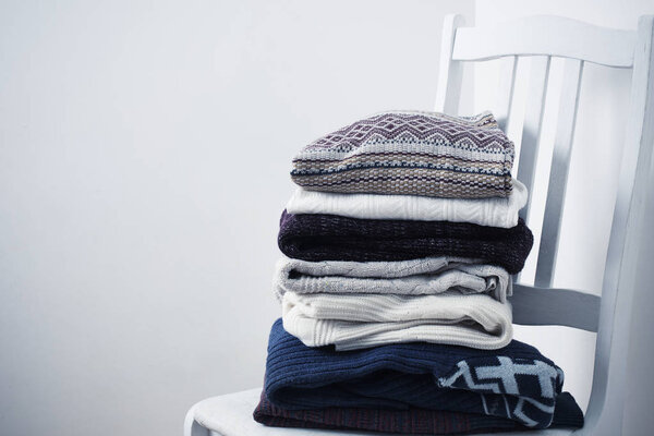 winter clothes on a chair against a white wall background