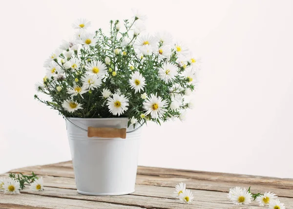 White flowers on bucket on wooden table — Stock Photo, Image