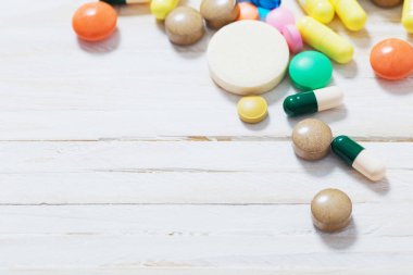 Beyaz ahşap arka plan üzerinde farklı hapları karıştırmak