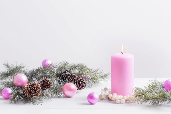 Weihnachtsdekoration mit rosa Kerze auf weißem Hintergrund — Stockfoto