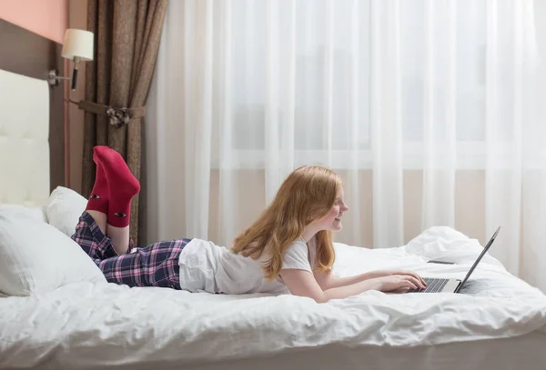 Chica adolescente con portátil en la cama — Foto de Stock