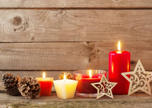 Kerstdecoratie met rode kaarsen op houten achtergrond — Stockfoto