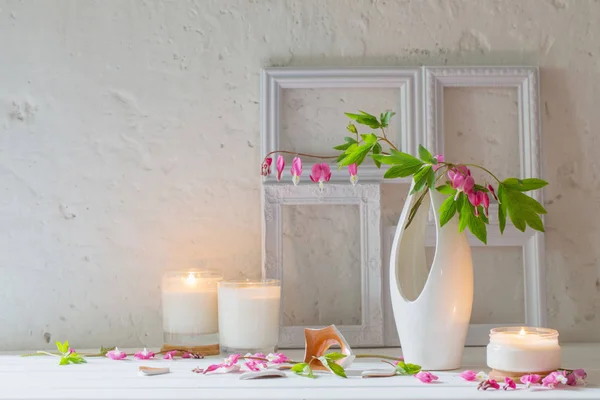 Fleurs dans un vase avec des bougies sur fond blanc mur — Photo
