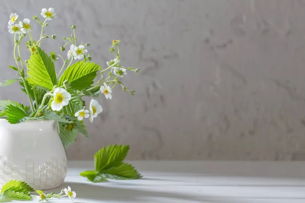 Bloemen van aardbei in vaas op oude achtergrond — Stockfoto