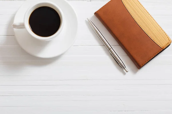 Bicchieri, taccuino, penna e tazza di caffè sul retro in legno bianco — Foto Stock