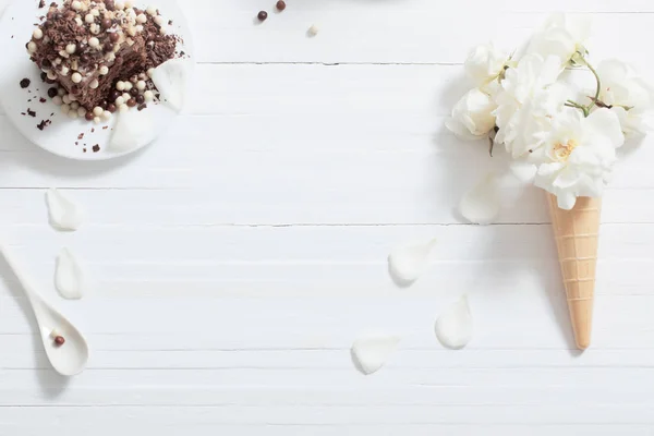 Flowers in waffle cone and chocolate cake  on white wooden backg — Stock Photo, Image