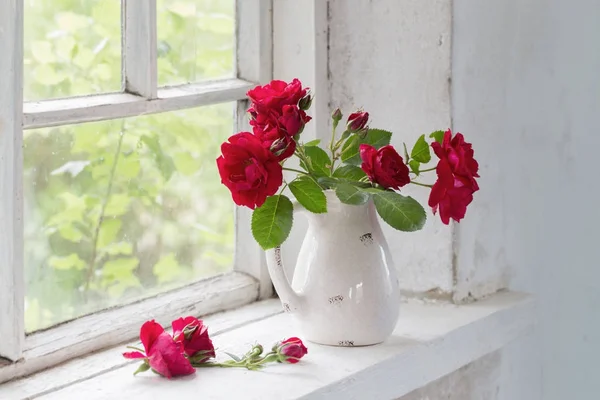 Rosas rojas en jarra en winwowsill — Foto de Stock