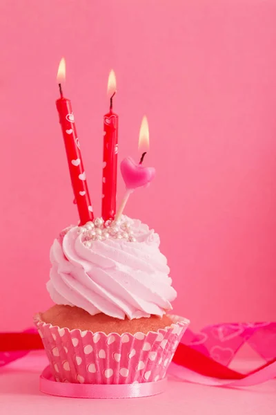 Cupcake com vela sobre fundo rosa — Fotografia de Stock