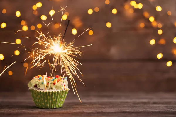 Cupcake met sparkler op oude houten achtergrond — Stockfoto