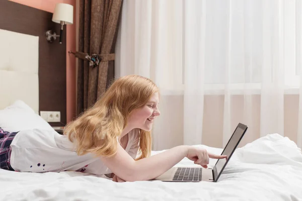 Adolescente menina com laptop na cama — Fotografia de Stock