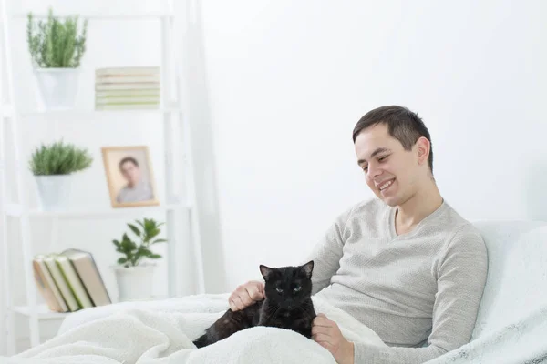 Unga män med svart katt inomhus — Stockfoto
