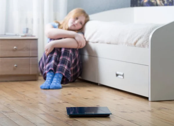 Triest tiener meisje met schubben op de vloer — Stockfoto