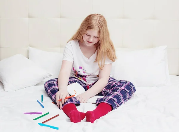 Menina adolescente desenha na cama — Fotografia de Stock