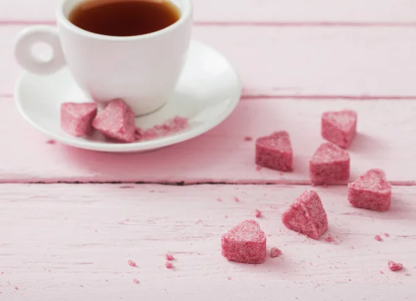 Açúcar rosa granulado em forma de coração e xícara de chá em — Fotografia de Stock