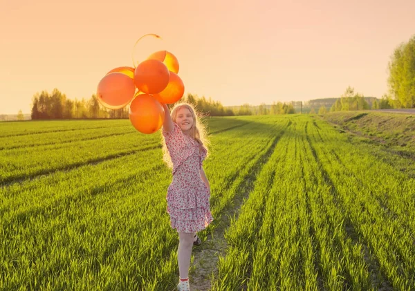 Glad tjej med ballonger på fältet — Stockfoto